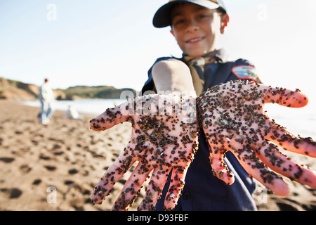 Mixed Race boy montrant les mains sales on beach Banque D'Images