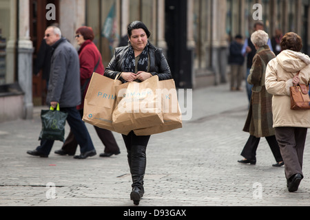 Une femme marche à travers le centre-ville de Liverpool transportant Primark shopping bags Banque D'Images