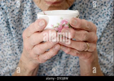Close up of an elderly woman's hands holding une tasse ou tasse de thé / café Banque D'Images
