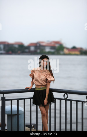 Thai Dame posant pour l'appareil photo en face de la rivière principale de Bangkok, le Chao Praya Banque D'Images