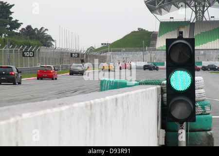 Feu vert et des voitures de course à l'approche d'un coin aigu au cours d'une journée circuit au circuit Sepang en Malaisie. Banque D'Images