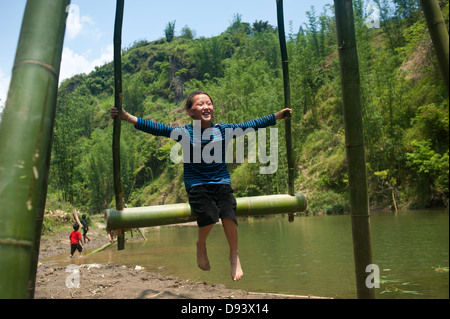 La région de Sapa, Vietnam du Nord - Enfants jouant sur le bambou fait par rotation de la rivière Banque D'Images