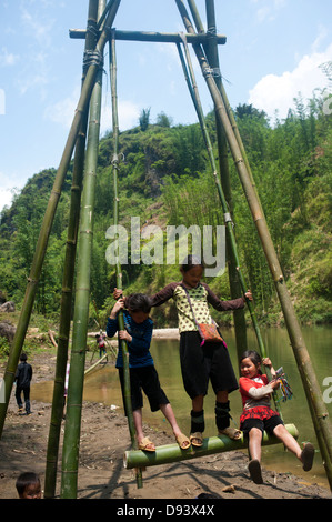 La région de Sapa, Vietnam du Nord - Enfants jouant sur le bambou fait par rotation de la rivière Banque D'Images