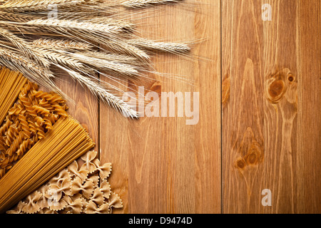 Les pâtes avec l'oreille de blé sur fond de bois. Différents types de pâtes de blé entier. Vue d'en haut. Copy space Banque D'Images