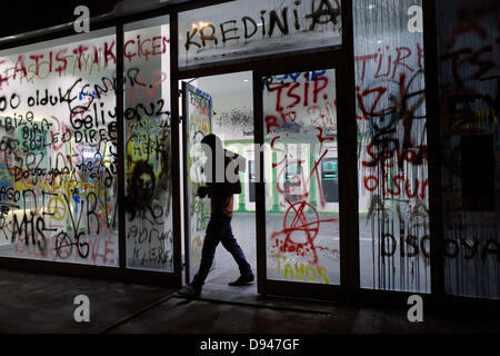 Istanbul, Turquie. 10 Juin, 2013. L'homme laisse une Garanti Bank succursale avec les fenêtres couvertes de graffitis anti-gouvernement sur la place Taksim, à Istanbul le 10 juin 2013. Credit : Konstantinos Tsakalidis/Alamy Live News Banque D'Images