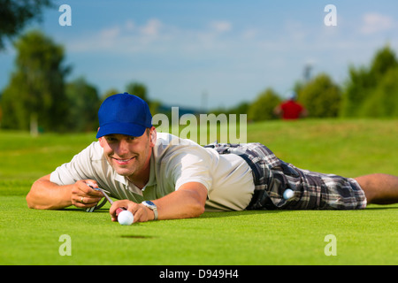 Jeune joueur de golf sur le putting, bien sûr il visant à mettre son shot Banque D'Images