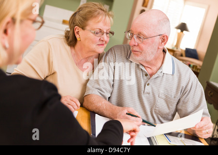 Senior Adult Couple going over articles dans leur maison avec l'Agent. Banque D'Images