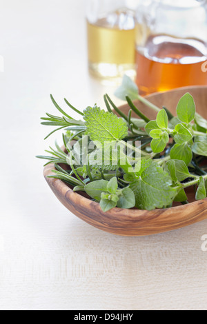 Les fines herbes dans un bol et bouteilles d'huile pour l'aromathérapie Banque D'Images