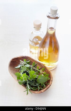 Les fines herbes dans un bol et bouteilles d'huile d'aromathérapie, elevated view Banque D'Images