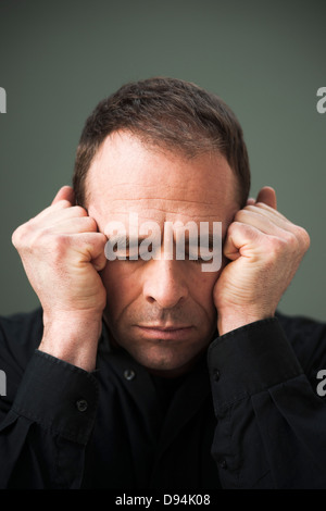 Head and shoulders Portrait of mature Man les yeux fermés et les poings en chef Banque D'Images