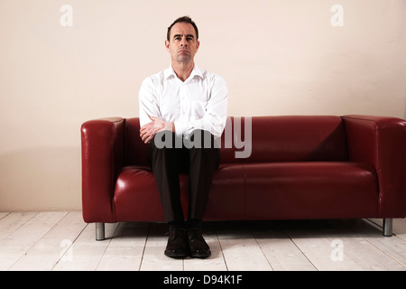 Man Sitting on Sofa, l'attente Banque D'Images