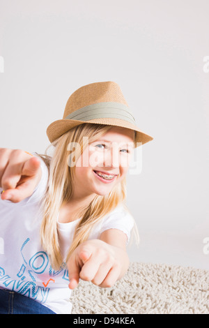 Portrait of Girl wearing Hat and Pointing at Camera in Studio Banque D'Images