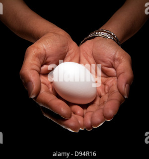 Close-up of Woman's Hands holding Egg, Studio Shot Banque D'Images