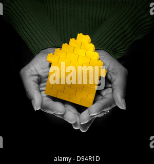 Close-up of Woman's Hands holding Yellow Brick House, Studio Shot Banque D'Images