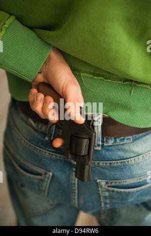 Close-up of Young Man holding Handgun behind Back Banque D'Images