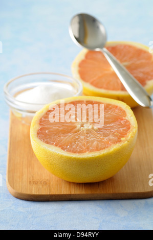 Close-up du pamplemousse réduit de moitié avec bol de sucre et la cuillère sur une planche à découper, Studio Shot Banque D'Images