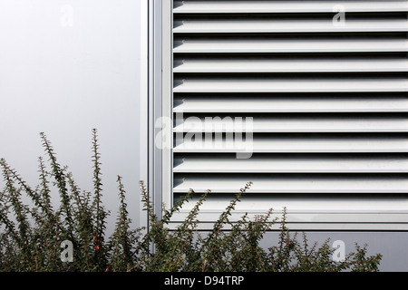 Le couvercle à claire-blanc pour l'ensemble de la climatisation en mur blanc avec le feuillage vert en premier plan Banque D'Images