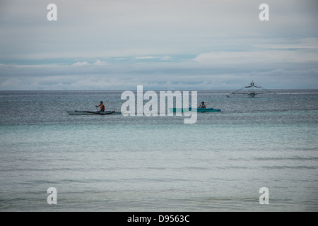 Deux philippins en pagayant sur bateaux traditionnels outrigger Dumaluan Beach sur l'île de Bohol, Philippines Visayas central dans Banque D'Images