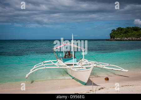 La pêche aux tangons traditionnel bateau amarré sur la plage de la côte Est de l'île de Malapascua, Cebu, Central Visayas, Philippines Banque D'Images