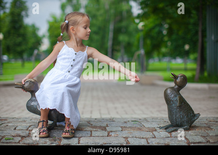 Petite fille nourrir les canards figure dans le parc Banque D'Images