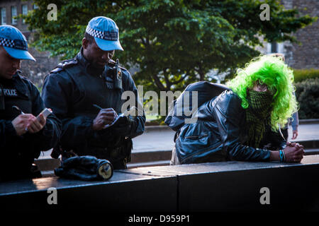 Londres, Royaume-Uni. 11 Juin, 2013. Les agents de police de rattraper leurs notes comme un anarchiste vert-wigged repose près le Parlement après une longue journée de protestation contre le sommet du G8, dans le West End de Londres. Crédit : Paul Davey/Alamy Live News Banque D'Images