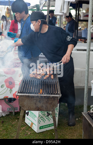 La cuisson des saucisses sur un marché en plein air, wc séparés. Beaucoup de fumée. Banque D'Images