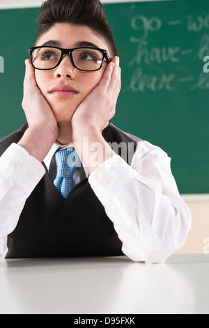 Boy Leaning on mains devant Tableau in Classroom Banque D'Images