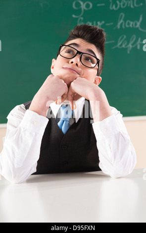 Boy Leaning on mains devant Tableau in Classroom Banque D'Images