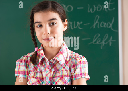 Head and shoulders Portrait of Girl in front of Chalkboard in Classroom Banque D'Images