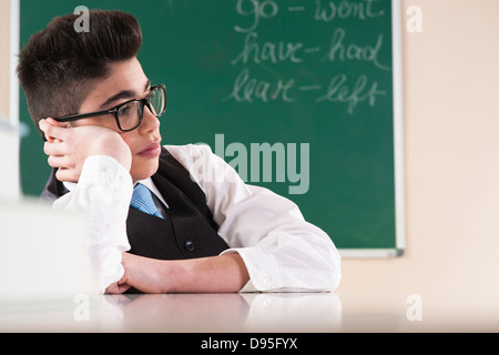 Boy Leaning on part en face du tableau en classe Banque D'Images