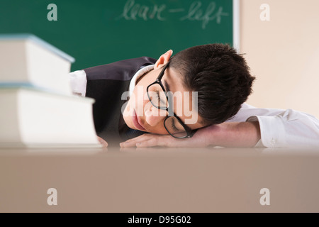 Le garçon endormi au bureau en face du tableau en classe Banque D'Images