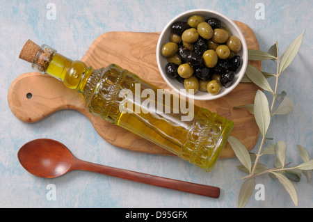 Vue de dessus de Bol d'olives et de bouteille d'huile d'olive sur une planche à découper avec cuillère en bois Banque D'Images