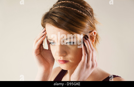 Head and shoulders portrait of teenage girl avec les mains sur sa tête en studio. Banque D'Images