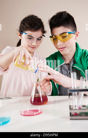 Garçon et fille portant des lunettes Pouring substance dans le bécher, Mannheim, Baden-Wurttemberg, Germany Banque D'Images