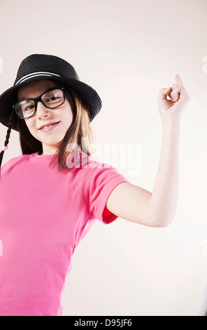 Portrait of Girl wearing Fedora et Horn-rimmed Eyeglasses, Smiling at Camera, Studio Shot Banque D'Images