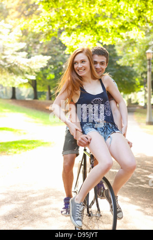 Jeune couple riding bike ensemble dans un parc sur une chaude journée d'été à Portland, Oregon, USA Banque D'Images