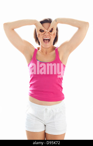Portrait of Young Woman wearing Tank top et short faire Mask avec les doigts dans Studio Banque D'Images