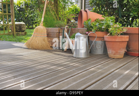 Différents accessoires de jardinage et de nettoyage sur une terrasse en bois Banque D'Images