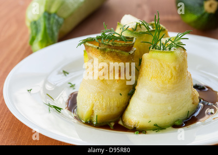 Rouleaux de courgettes avec une garniture sur une assiette blanche Banque D'Images