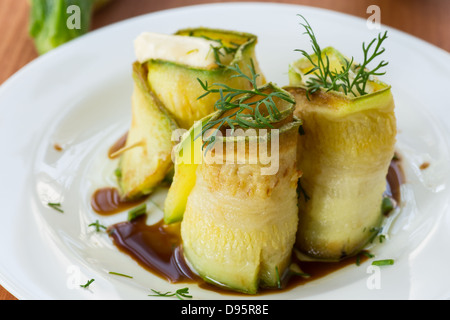 Rouleaux de courgettes avec une garniture sur une assiette blanche Banque D'Images