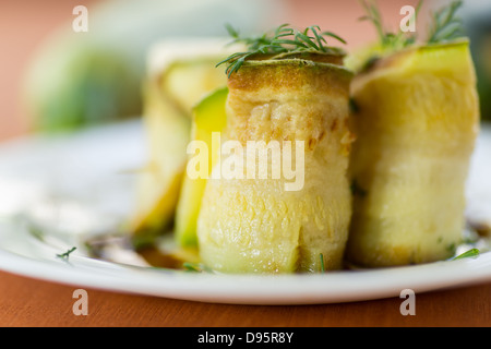 Rouleaux de courgettes avec une garniture sur une assiette blanche Banque D'Images