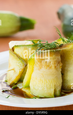 Rouleaux de courgettes avec une garniture sur une assiette blanche Banque D'Images