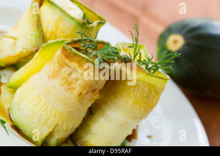 Rouleaux de courgettes avec une garniture sur une assiette blanche Banque D'Images