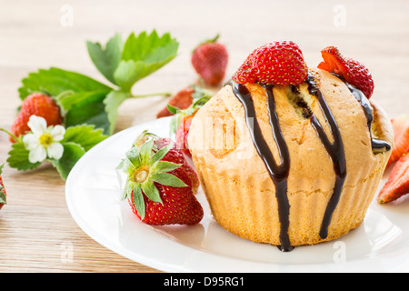 Muffins à la fraise avec une sauce au chocolat sur une plaque blanche Banque D'Images