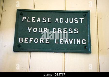 'Veuillez ajuster votre robe avant de partir" - un signe chez les hommes à la toilette à Bluebell Railway East Sussex, Royaume-Uni. Banque D'Images