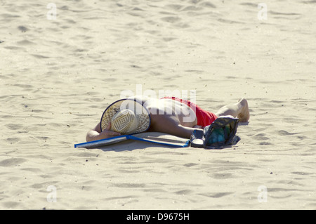 Man est posée sur le sable et de prendre une douche solaire Banque D'Images