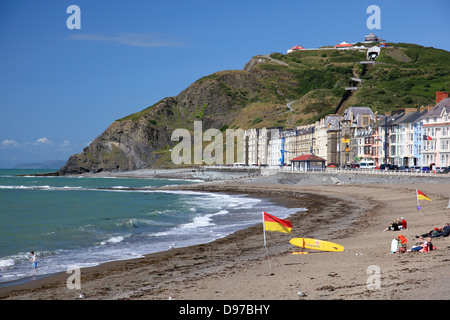 La plage et la promenade à Aberystwyth avec drapeaux de la RNLI pour afficher une zone de baignade en toute sécurité et d'un sauveteur en service Banque D'Images