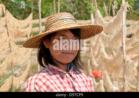 Jeune jolie fille portant un chapeau de paille en face de pousses de séchage le Myanmar (Birmanie) Banque D'Images