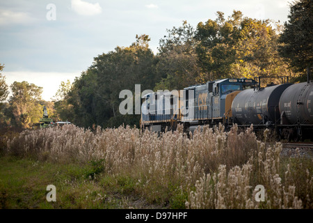 Deux moteurs CSX tirer lentement sur un train de marchandises à travers une région rurale près de Hawthorne, en Floride. Les équipes de réparation travaillent sur la piste. Banque D'Images