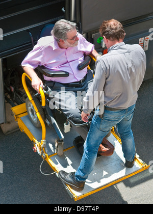 Vue supérieure de l'homme handicapé en fauteuil roulant d'être aidé sur l'entraîneur touriste rampe - France. Banque D'Images